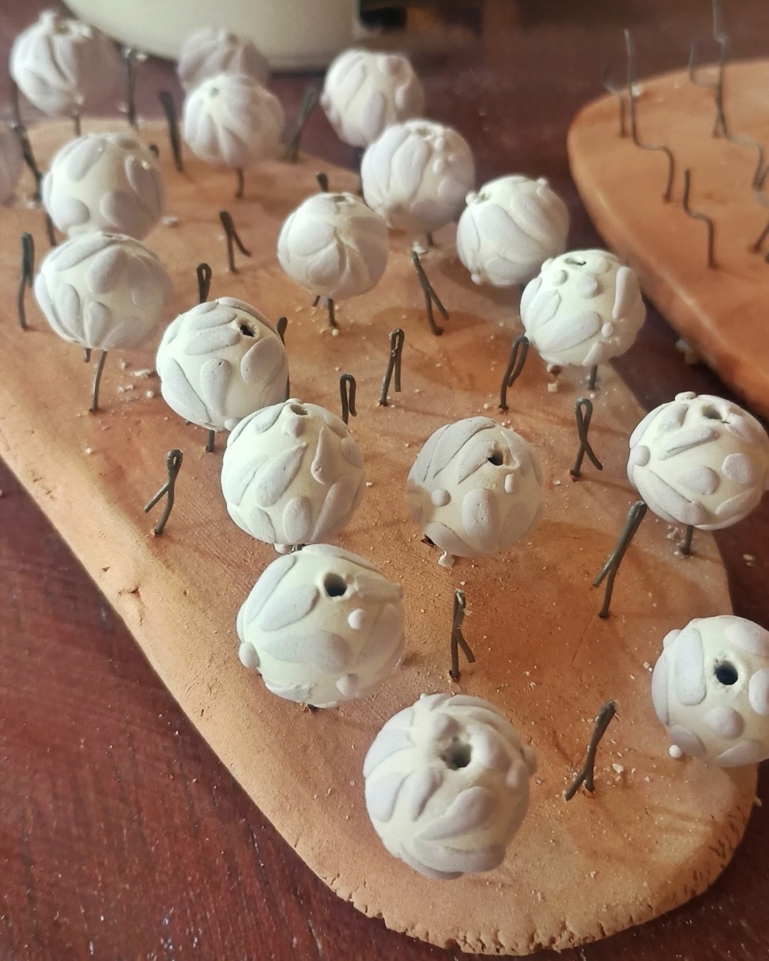 Unfired handmade lasso beads drying on pins before decoration and threading