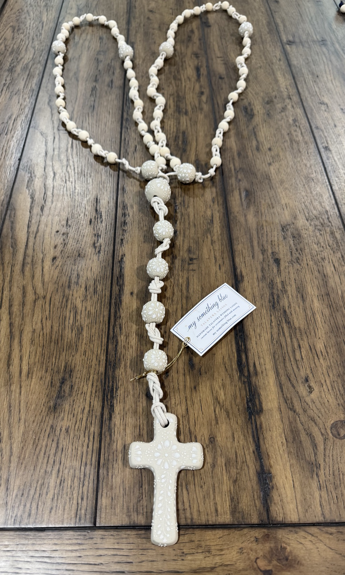 Ivory ready-made Talavera lasso with braided cotton cord, ceramic cross, and product tag