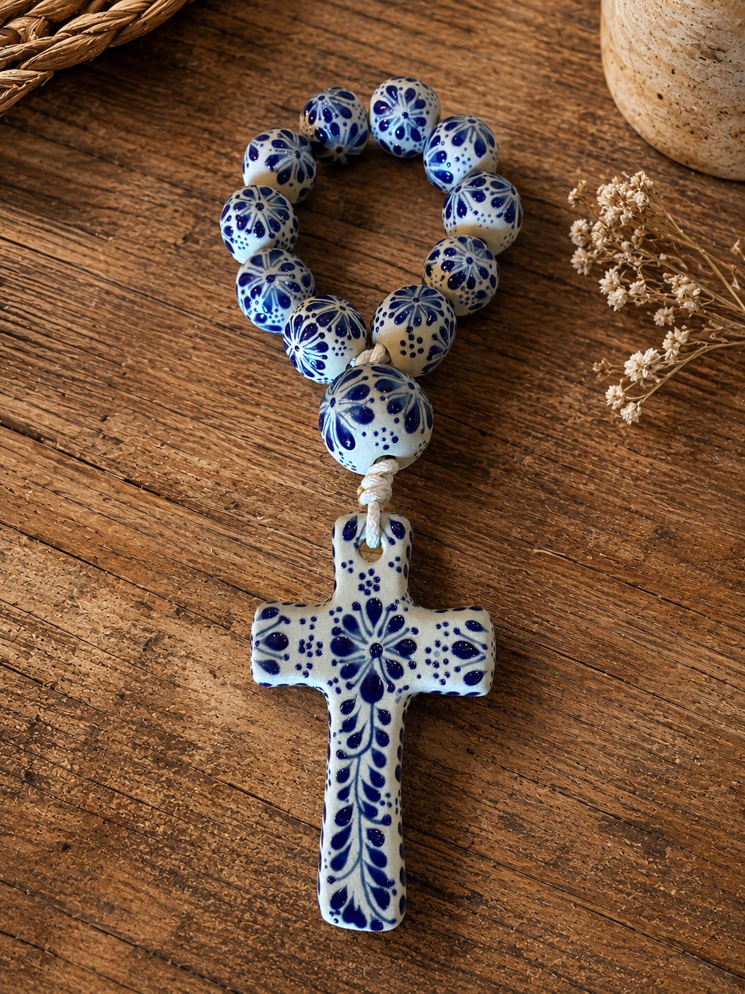 Talavera-style blue-and-white rosary beads with a ceramic cross on a wooden table
