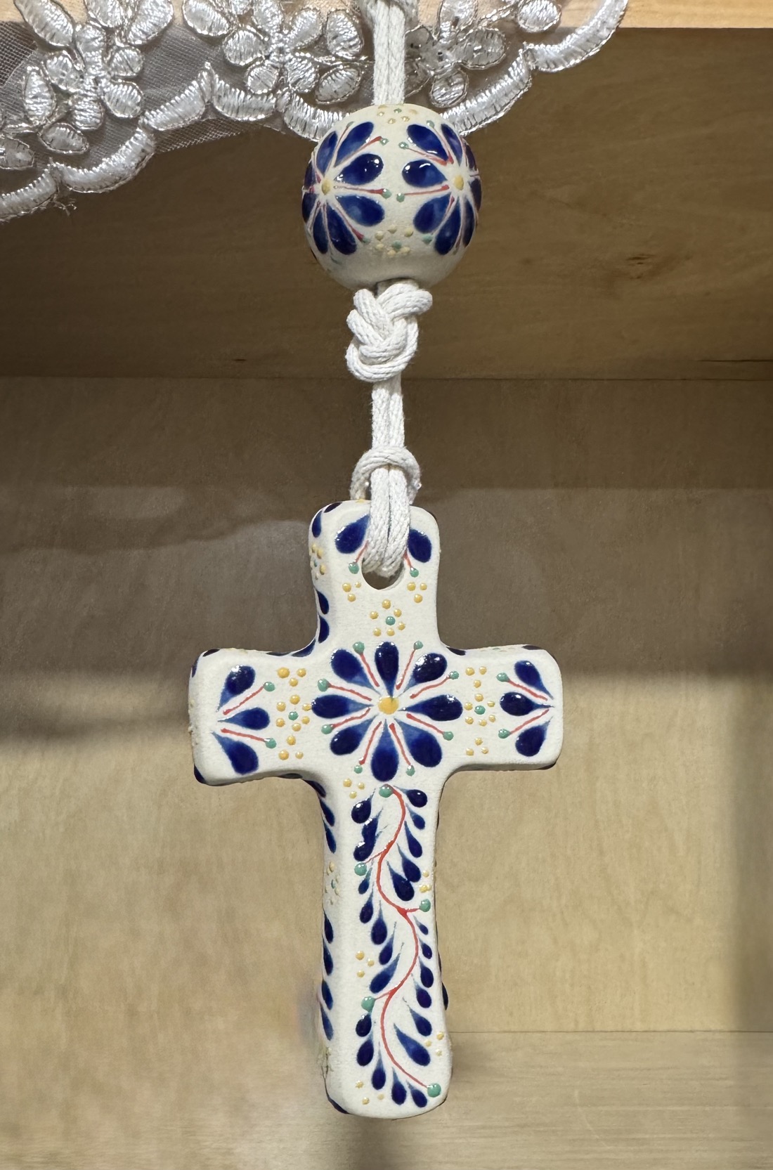 Talavera-style blue-and-white ceramic cross detail with handmade beadwork